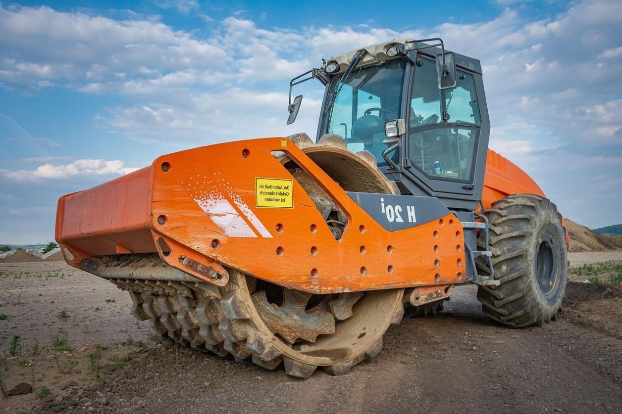 Soil compactor working under a clear blue sky
