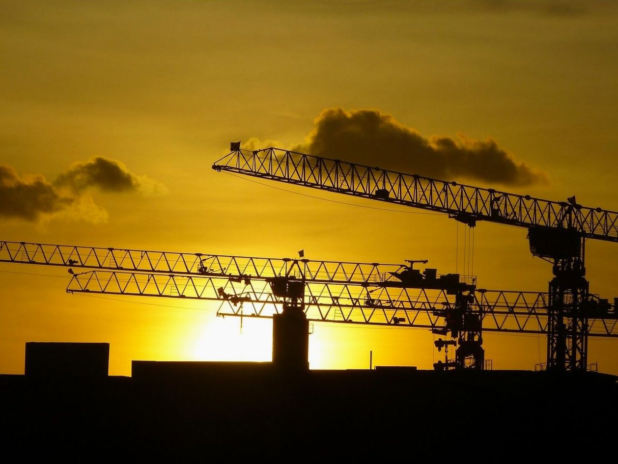 Tower cranes silhouetted against the sunset on a Finnish construction site