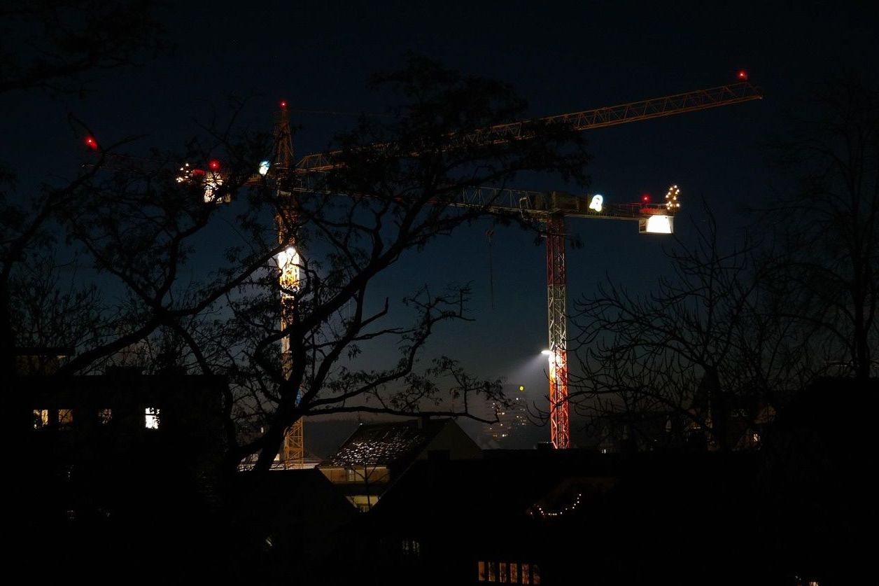 Tower cranes lit up at night above a residential neighbourhood