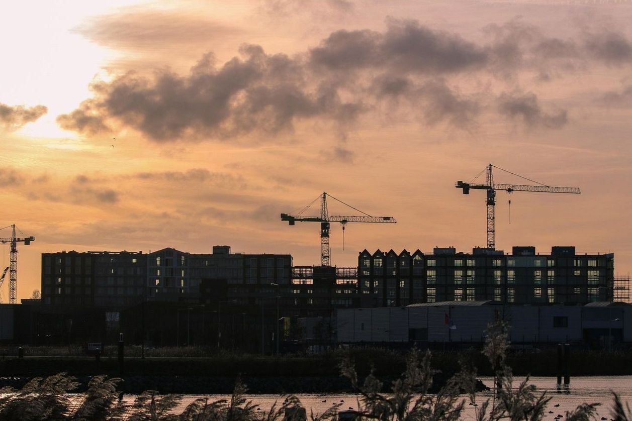 Apartment blocks under construction by the water at dusk