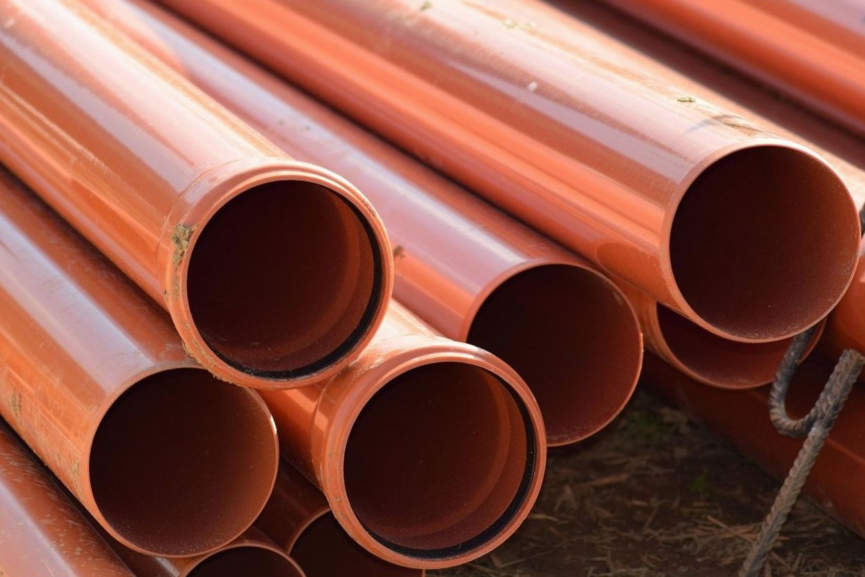 Orange utility pipes stacked and ready for installation