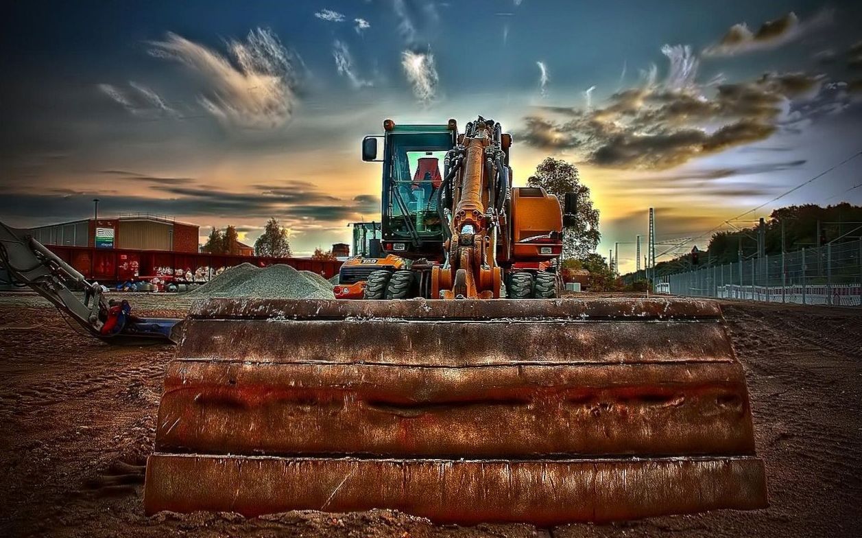 Excavator bucket against a dramatic sunset sky