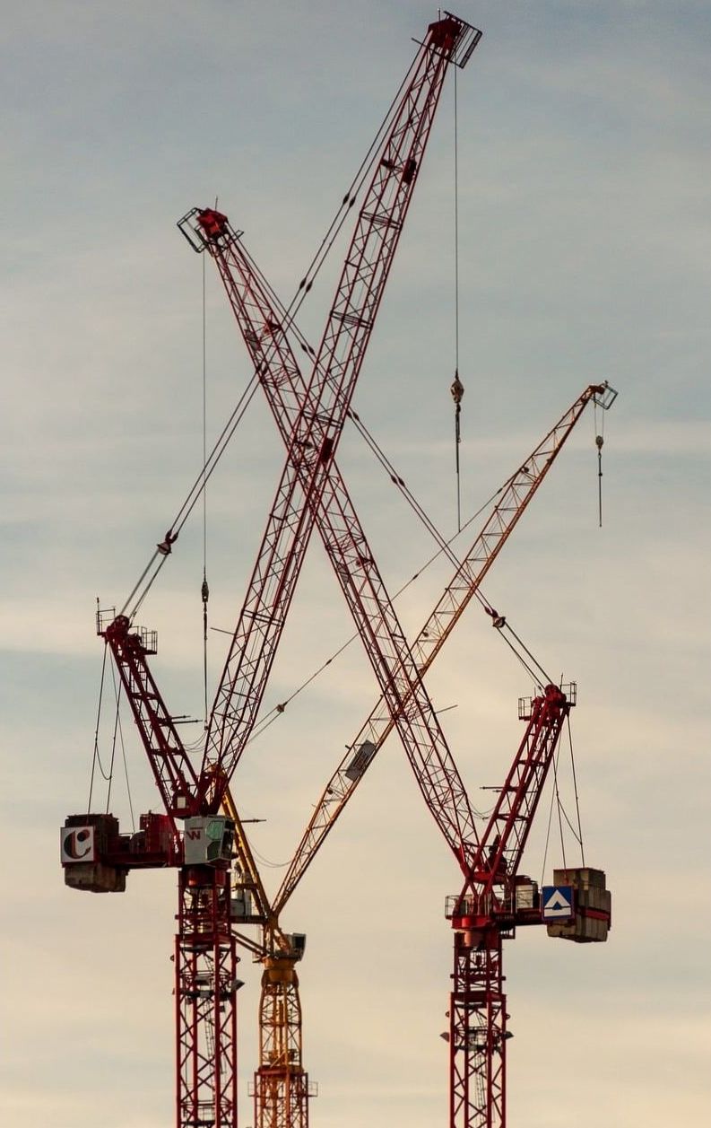 Red tower cranes against an evening sky